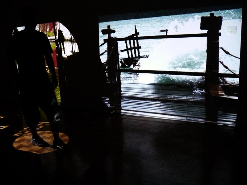 The Oracle's projected video walls showing imagery, with a visitor walking through the space